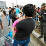 Una mujer venezolana sostiene a su hijo mientras su marido hace cola para recibir comida del régimen en Urena, cerca de la frontera colombiana