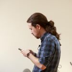 El secretario general de Podemos, Pablo Iglesias, mira su móvil poco antes de comparecer ante los medios de comunicación hoy en el Congreso.