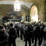Una de las imágenes del 1-O que más impacto ha tenido es la de un grupo de Mossos entrando a toda prisa a la Cámara catalana para refugiarse y esperar refuerzos, como se ve en la imagen. Los antidisturbios disponibles para la jornada estaban en las movilizaciones ante la Policía Nacional y en Gerona