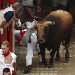 El toro "Huracán"de la debutante ganadería salmantina de Puerto de San Lorenzo engancha a un mozo en el callejón, a la entrada a la plaza de toros, durante el tercer encierro de los Sanfermines 2017