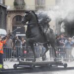 Operarios limpian la escultura de Franco, sobre la que manifestantes habían arrojado pintura.