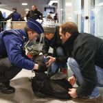 Un agente de policía belga registra el equipaje de dos pasajeros en la estación de trenes Midi de Bruselas la pasada Nochebuena