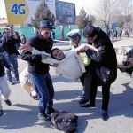 Un hombre traslada a un herido a una zona segura después del atentado, ayer, en Kabul