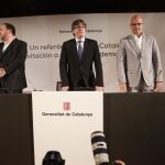 El presidente de la Generalitat, Carles Puigdemont, en presencia del vicepresidente, Oriol Junqueras, y el consejero de Asuntos Exteriores, Relaciones Institucionales y Transparencia, Raúl Romeva