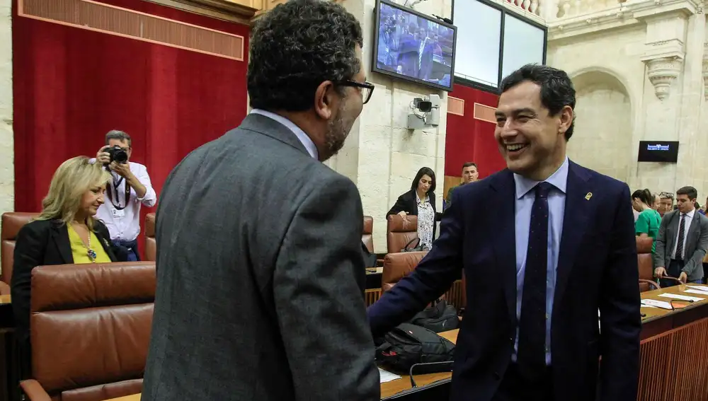 El presidente del Gobierno andaluz, Juanma Moreno, saludó ayer antes del Pleno al portavoz parlamentario de Vox, Francisco Serrano / Foto: Manuel Olmedo