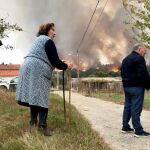 Dos vecinos junto a un incendio forestal esta mañana en las proximidades del municipio O Carballiño (Orense)