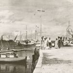 En la foto se ve una figura femenina parecida a Earhart sentada en un muelle y a la derecha un avión que podría ser el de la aviadora