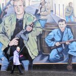 Una mujer camina ante uno de los muchos carteles probritánicos que sobreviven en las calles de Belfast después de 20 años de paz