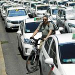 Un ciclista intenta hacerse paso entre la marea de taxis que ayer colapsó el Paseo de la Castellana/ Efe