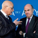 El ministro de Economía, Industria y Competitividad, Luis de Guindos (d), escucha al presidente de Banco de Sabadell Josep Oliu.