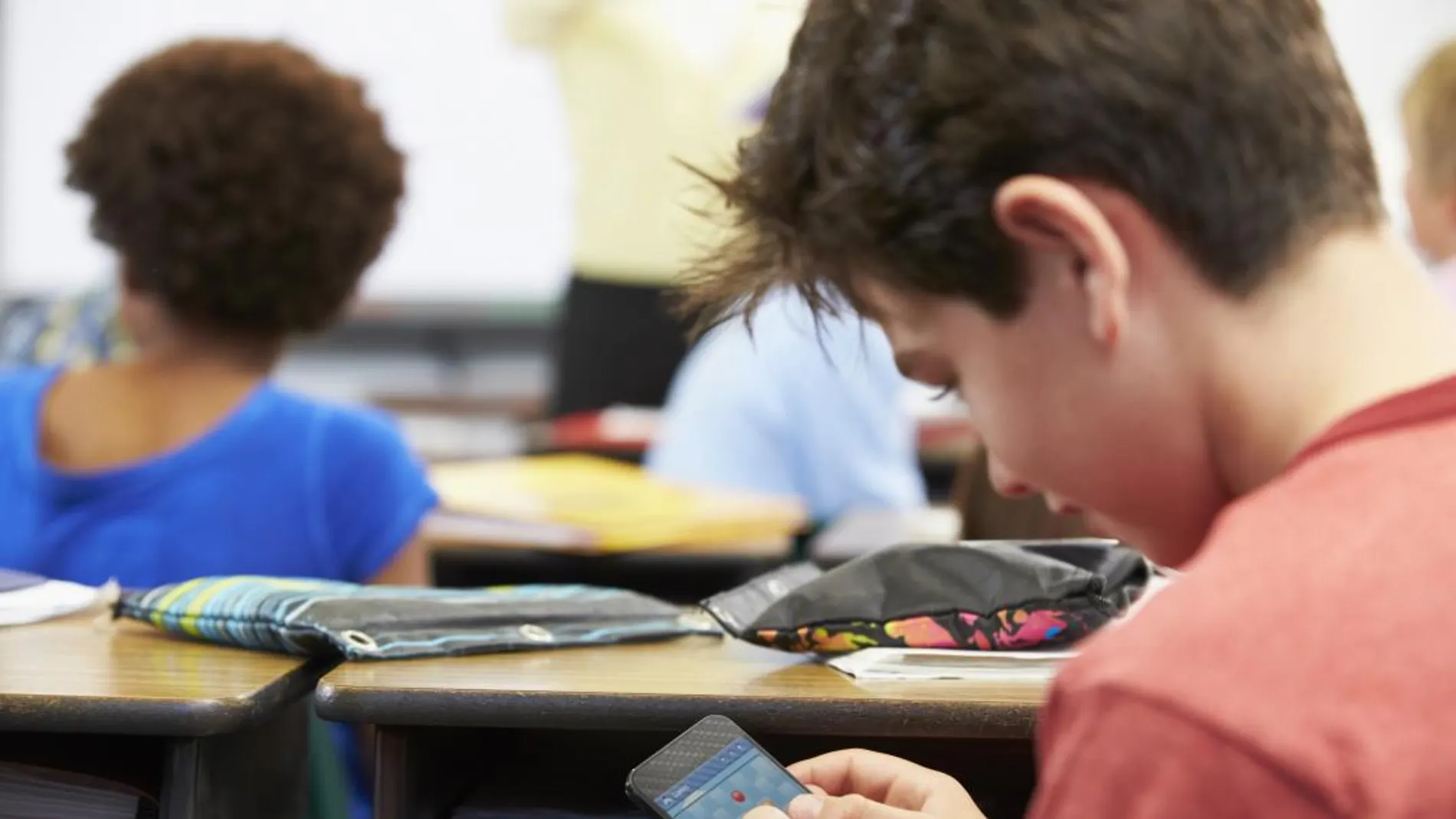 Un niño jugando con el móvil en el colegio