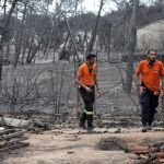 Dos miembros de personal de rescate buscan a posibles víctimas en una zona afectada por los incendios en Mati, Ática (Grecia) / Foto: Efe