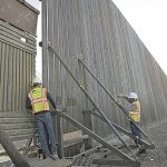 Dos empleados aseguran una sección del muro que separa México de California