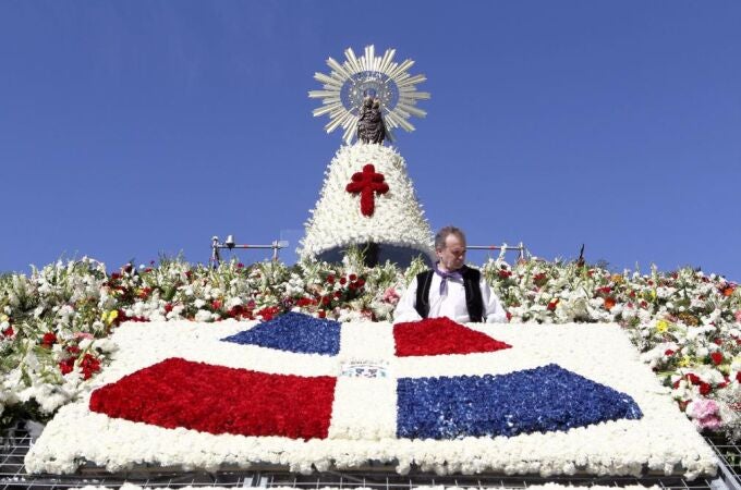 Una ofrenda de flores con la bandera de Santo Domingo destaca sobre el tradicional y colorido manto de la Vírgen del Pilar