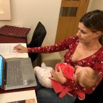 Una madre trabaja con su hijo en brazos