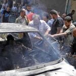 Un grupo de sirios trata de sacar a un hombre quemado en un ataque en Damasco perpetrado por las fuerzas leales a Asad