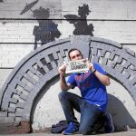 Un espontáneo posa delante de una de las obras que Bansky ha hecho en Nueva York