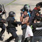 Varios policías se llevan a uno de los detenidos en las afueras del estadio de Bangkok