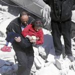 Un hombre lleva en brazos a una niña tras un bombardeo en Douma