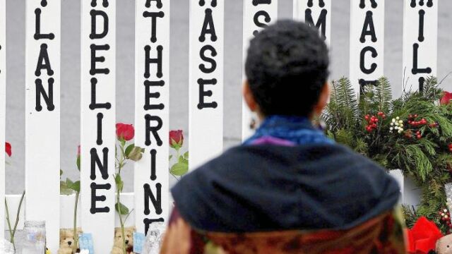 Una mujer observa una valla con los nombres de los niños asesinados