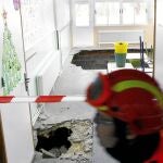 Un bombero pasa ante el socavón en el suelo de un aula del colegio público Hispanidad de Santa Pola producido a las 9:10 de la mañana y que ha causado heridas a nueve niños y una profesora.