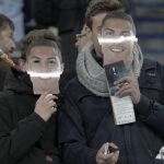 Dos aficionados se colocan unas caretas con la imagen de Cristiano Ronaldo antes del comienzo del partido. EFE/JuanJo Martin.
