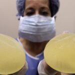 Una enfermera muestra dos implantes mamarios PIP.