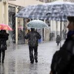 Varias personas pasean bajo la nevada en Segovia