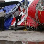 La policía indonesia levanta la lona que cubre la cola del avión