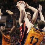 El alero del Laboral Kutxa Fernando san Emeterio (c) lucha el balón ante Serhiy Lishchuk (d) y Romain Sato, del Valencia Basket Club.