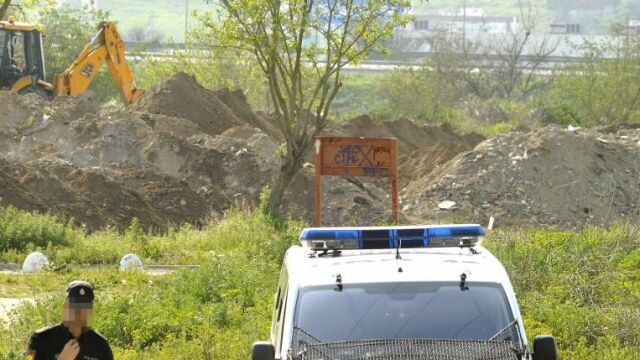 Una patrulla de Policía vigila la escombrera de Camas, con la máquina excavadora trabajando al fondo