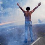 Un manifestante levanta los brazos delante la policía, durante una manifestación en Caracas