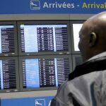 Dos hombres miran el panel de información del aeropuerto parisino Charles de Gaulle con el vuelo AF755.