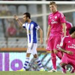 Los jugadores de la Real Sociedad celebran su victoria mientras Marcelo (d), del Real Madrid, se arrodilla al término del encuentro