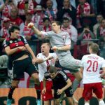 Mats Hummels trata de rematar de cabeza ante la salida del portero polaco, Wojciech Szczesny