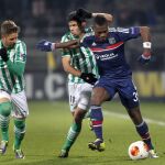 El jugador del Olympique Lyon, Henri Bedimo (d) controla el balón junto al defensa Juanfran Moreno (C) del Real Betis