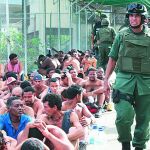 Un agente de la Guardia Nacional pasea junto a un grupo de internos en la prisión de El Rodeo, a las afueras de Caracas