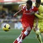 El delantero colombiano del Sevilla Carlos Bacca disputa un balón con el defensa brasileño del Villarreal Gabriel Paulista (d), durante el partido disputado hoy en El Madrigal