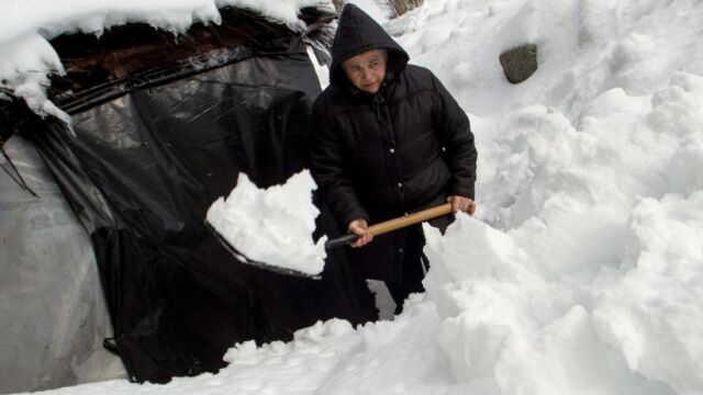 Una vecina de O Cebreiro, en Lugo, despeja su vivienda de nieve con una pala. EFE/Eliseo Trigo