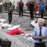 Antonio Martín Marugán, en primer término a la derecha, pasa por delante de algunos cadáveres tras el accidente del miércoles de la semana pasada con su teléfono móvil en las manos