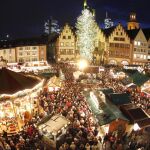 Cientos de personas en un mercadillo navideño de Frankfurt, con un gran árbol de Navidad iluminado.