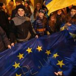 Manifestantes posan con la bandera Europea y de Ucrania durante una manifestación frente a la embajada de Ucrania en Varsovia (Polonia).