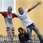 Los tres tres inmigrantes muestran su alegría tras acceder a Melilla a través de la valla fronteriza con Marruecos