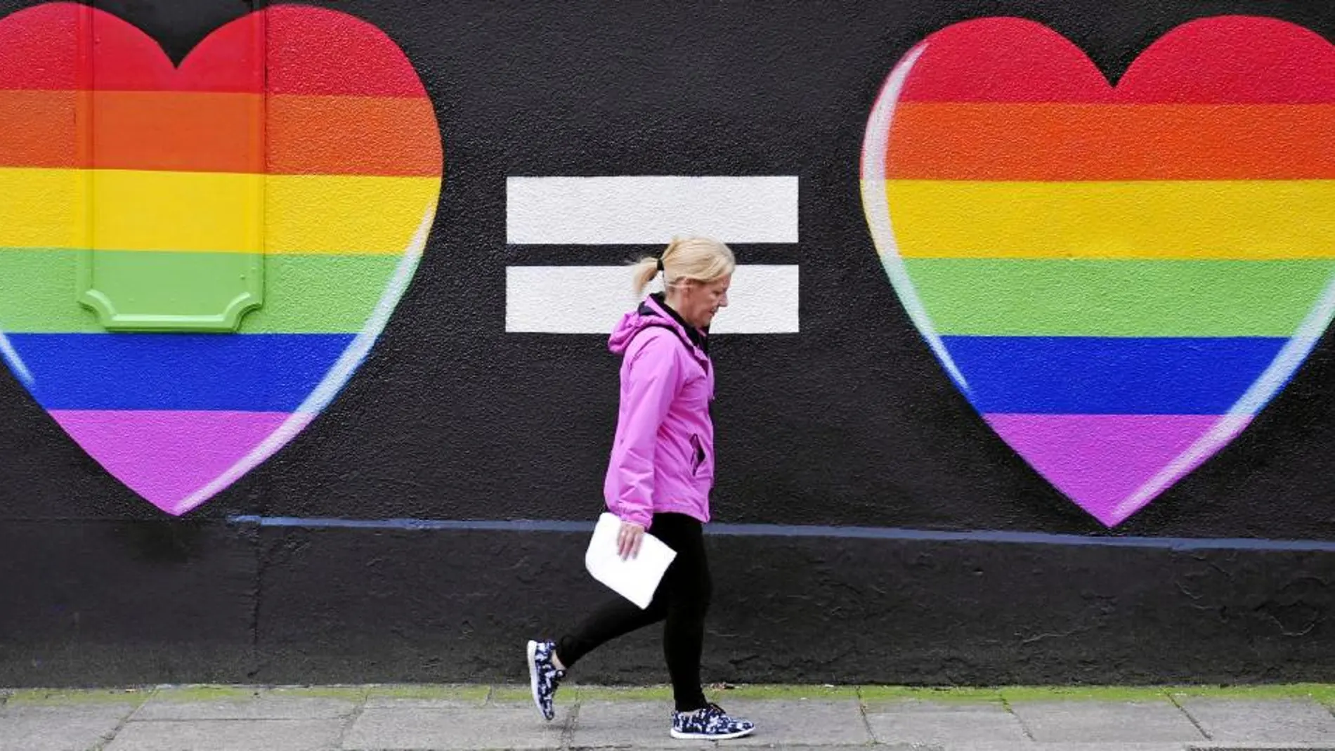 Una mujer pasea frente a un grafiti a favor de los enlaces gays