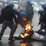 Un agente permanece en el suelo tras recibir el impacto de un cóctel molotov.