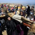 Miembros de las distintas cofradías y público se mezclan en Viernes Santo durante la procesión a la playa de la Semana Santa Marinera para honrar a los muertos en el mar. Imagen de archivo.