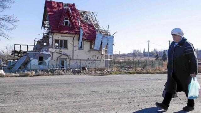 Una ucraniana camina delante de una casa destrozada por los combates que siguen activos al este de Ucrania