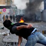 Un manifestante lanza una piedra contra la Polícía en el centro de Teherán el pasado sábado