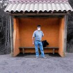 Un hombre espera en una parada de autobús cubierta de ceniza en Ensenada (Chile)