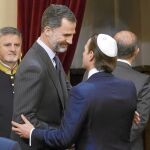 El Rey saluda a uno de los asistentes tras el acto en el Senado por la memoria del genocidio nazi